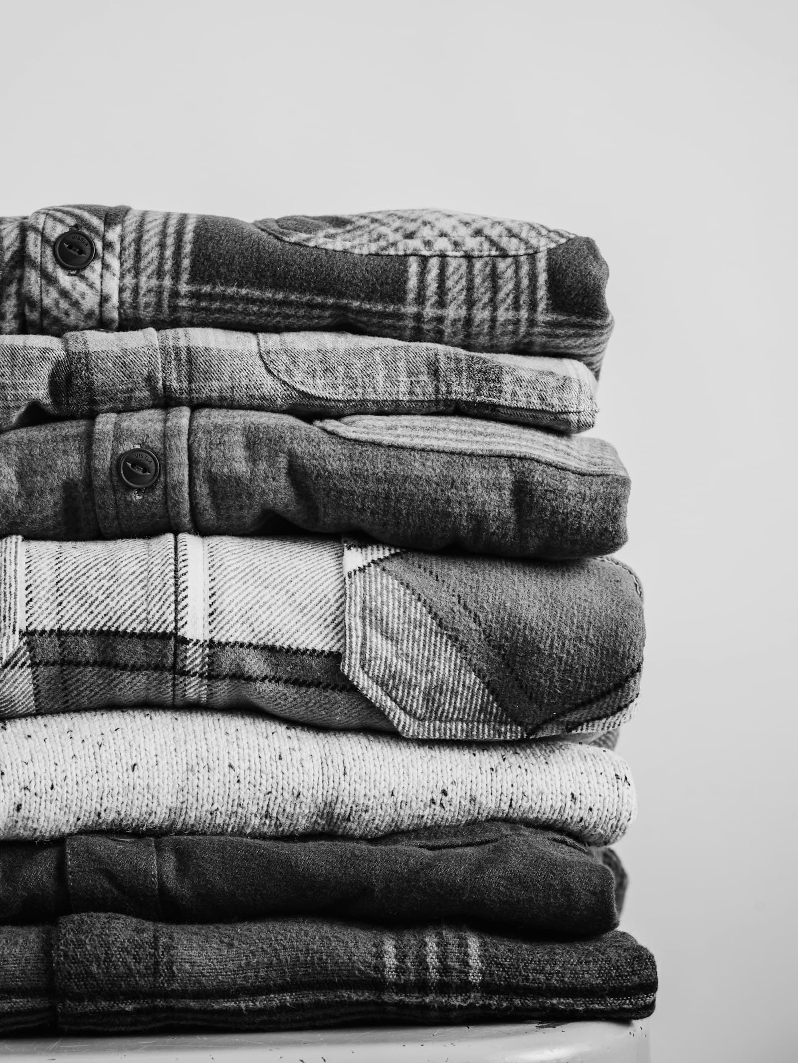 A stack of folded flannel shirts in black and white