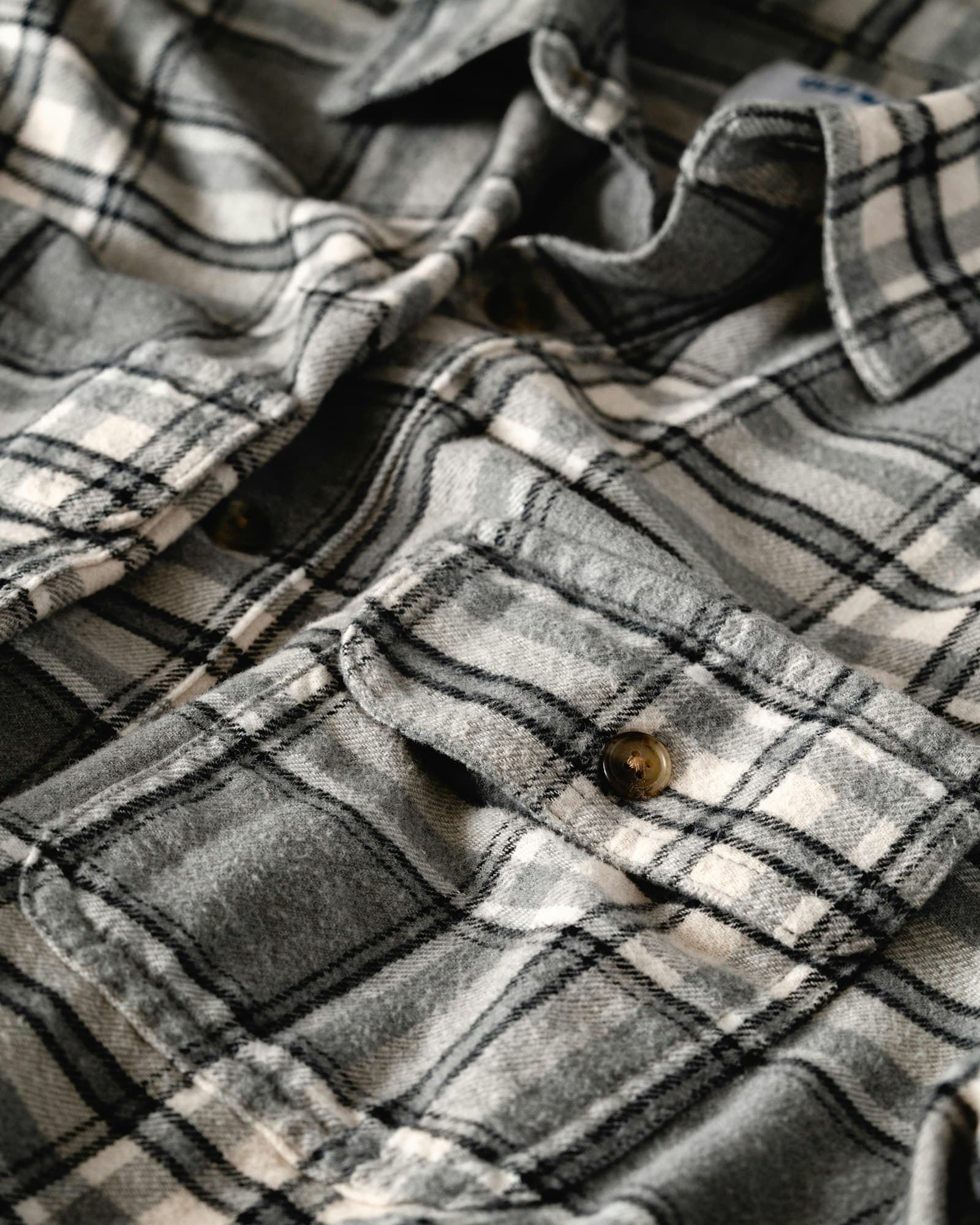 Grey and white plaid flannel shirt with a buttoned pocket