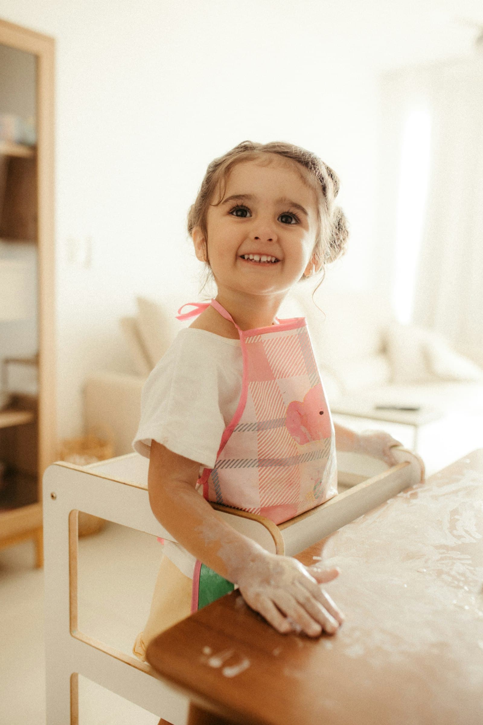 A smiling young girl wearing an apron at a table