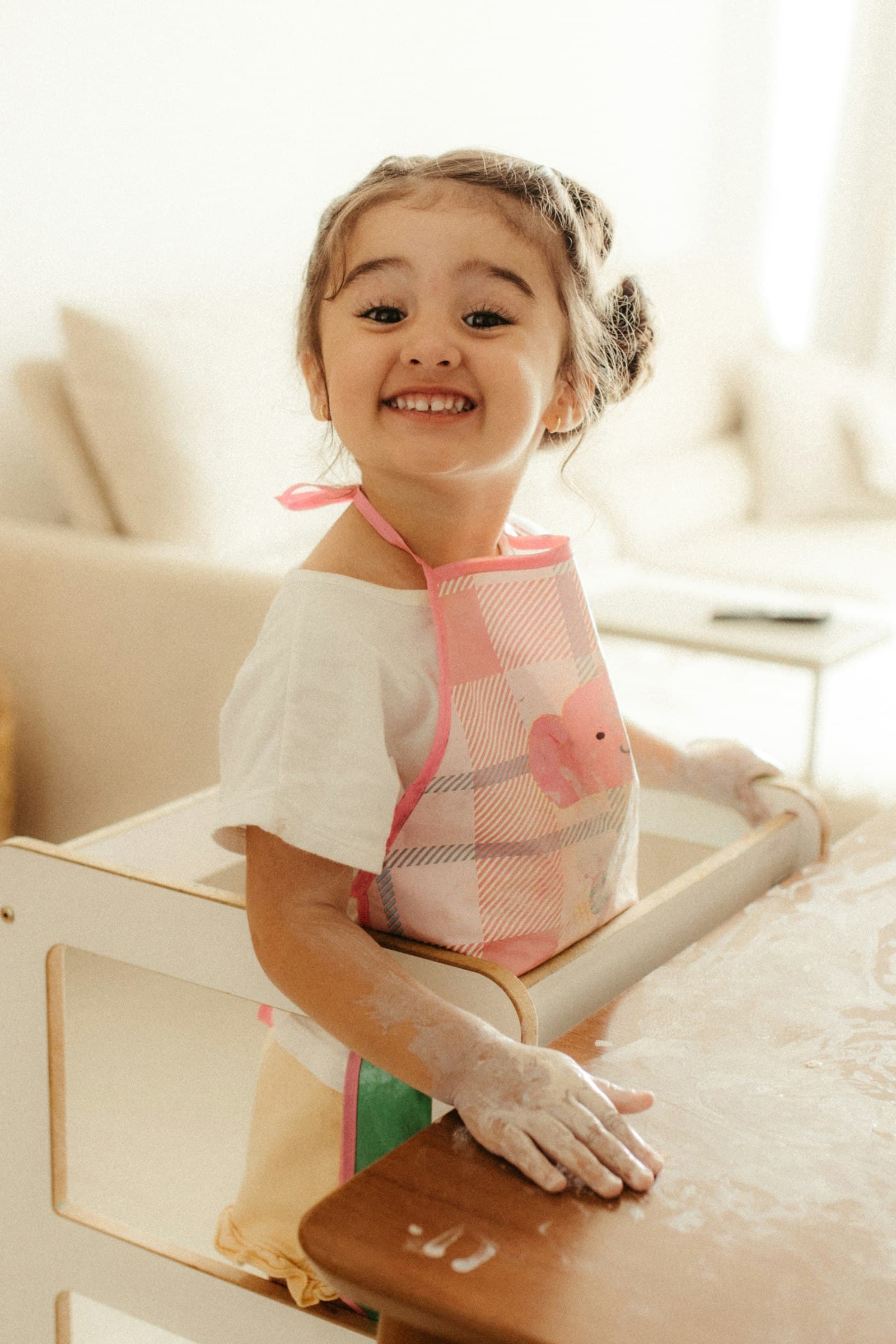 A smiling girl wearing an apron in a kitchen